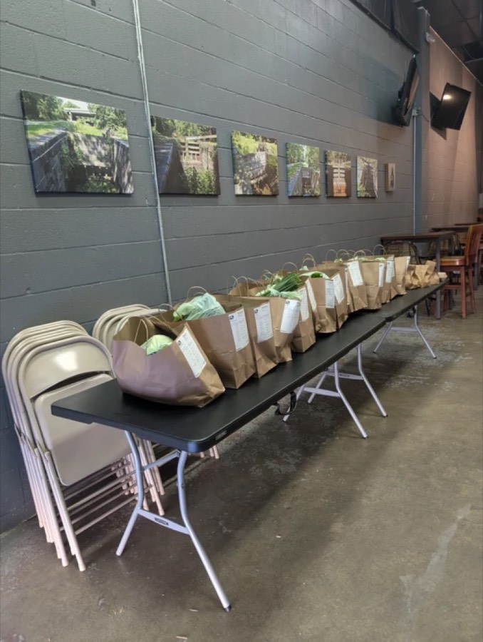 Framed photographs of the C&O Canal locks on the taproom wall, above CSA farm-share bags