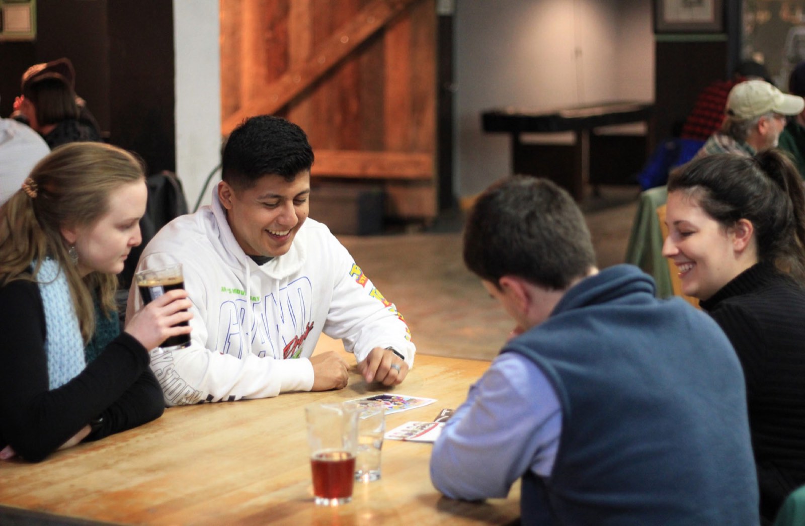 Friends laughing over beers at a taproom table